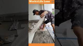 Tiler is using a notched trowel to apply mortar to the substrate before positioning a large tile [upl. by Lorianne787]